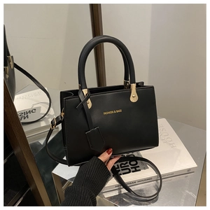 Detail of black leather tote bag with gold lettering and adjustable shoulder strap
