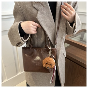 Brown leather bucket bag detail with letter embossing and cute teddy dog charm