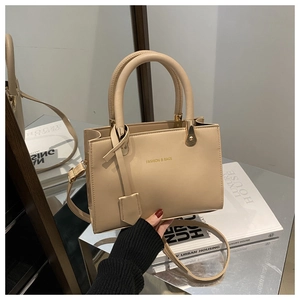 Detail of beige structured tote bag with gold hardware and detachable shoulder strap