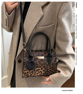 Détail du sac léopard avec poignée ronde noire et breloque en boule de fourrure douce
