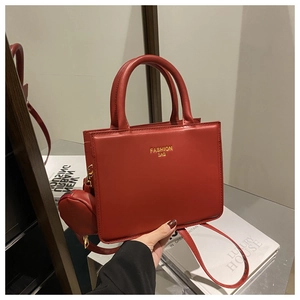 Detail of red leather tote bag with gold logo, mini pouch, and adjustable shoulder strap