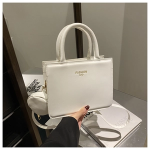 Detail of white square handbag with gold logo and round coin purse charm