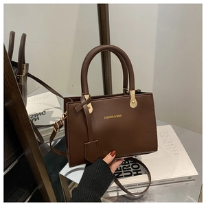 Detail of dark brown matte leather tote with golden lettering and rigid top handle