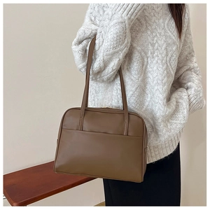 Détail d'un sac à épaule en cuir marron avec poche frontale et fermeture éclair dorée