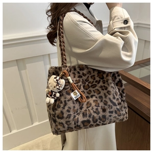 Detail of plush leopard print shoulder bag with woven strap and cute bear charm