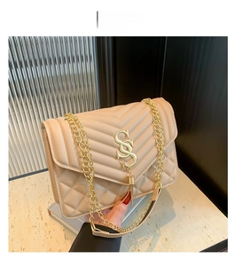 Detail of khaki shoulder bag with V-shaped quilting, gold chain and tassel charm