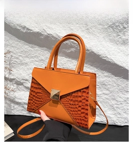 Detail of orange brown tote bag with crocodile texture contrast and gold square buckle