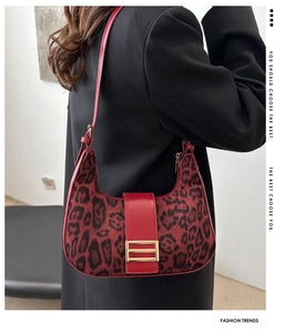 Detail of red leopard print crescent bag with gold buckle and smooth leather strap