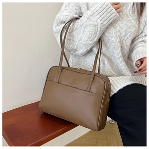 Gros plan d'un sac porté épaule vintage marron sur un pull en maille blanc et texture
