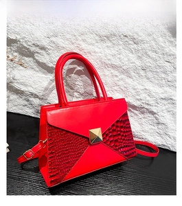Detail of red crocodile texture embossing and gold metal rivet buckle on handbag