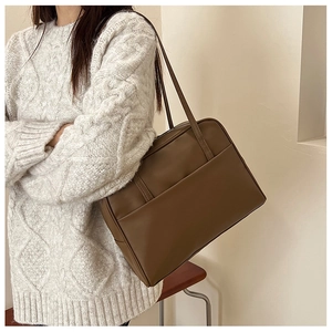 Détail d'un sac cabas vintage en similicuir marron foncé avec fines anses et fermeture éclair