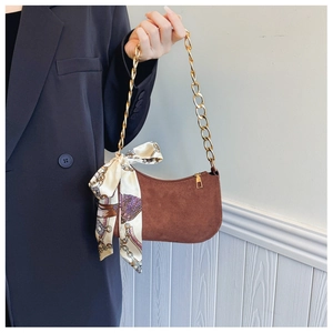 Detailed close-up of brown frosted handbag with gold chunky chain and printed silk scarf