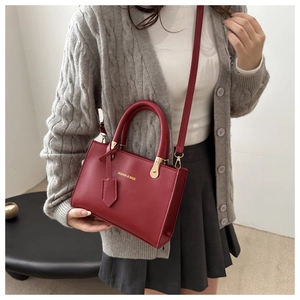 Detail of red leather tote bag with gold lettering and adjustable shoulder strap