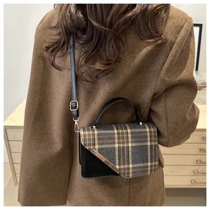 Detail view of vintage plaid crossbody bag worn on shoulder over a brown blazer