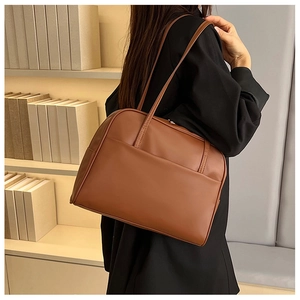 Sac fourre-tout marron avec poche frontale porté par un mannequin dans une bibliothèque