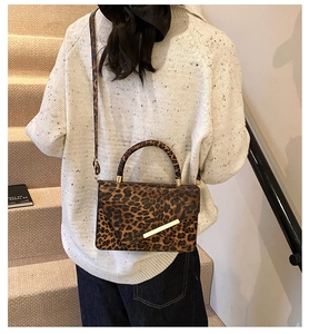 Leopard print crossbody bag shown on model wearing a white knit sweater in a cozy interior