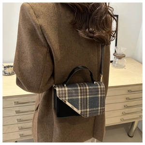 Detailed back view of vintage plaid crossbody bag with V-shaped metal trim and leather strap