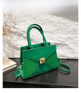 Detail of green crocodile embossed handbag with gold stud and envelope flap