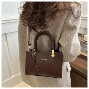 Detail of dark brown tote bag with FASHION & BAGS gold lettering and adjustable strap