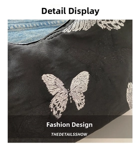Macro shot of silver butterfly embroidery on black fabric showing fine wing textures