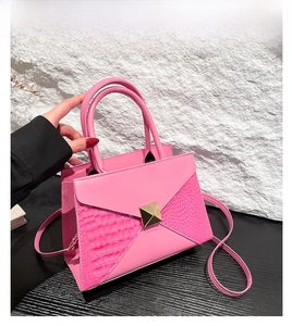 Detailed view of pink croc-embossed leather tote bag with golden metal hardware