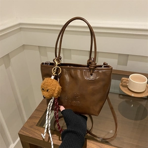 Vintage brown faux leather bucket bag with plush puppy pendant and logo detail