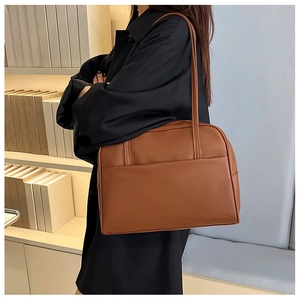 Vue détaillée d'un sac à bandoulière en cuir marron dans une bibliothèque au style épuré