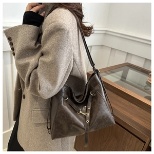 Detail of vintage brown leather tote bag showing golden buckle and fine texture on shoulder strap