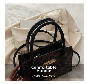 Détail du sac à main imprimé léopard avec poignées noires et plaque en métal dorée