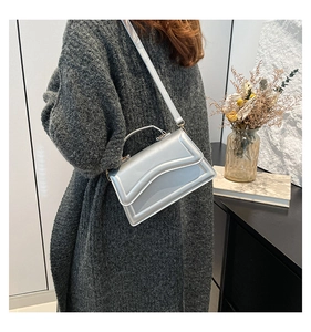 Detail der silbernen Metallic-Tasche mit Wellensteppung und verstellbarem Gurt