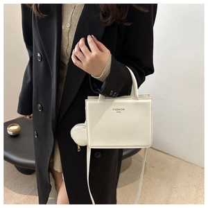 Close-up of white minimalist square tote bag with top handle and round detachable coin purse