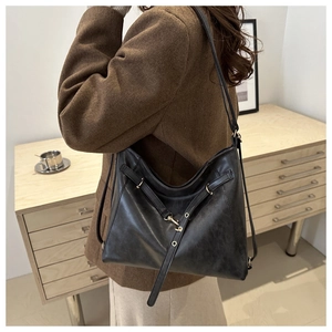 Detail of black leather tote bag showing soft texture and decorative metal ring detail