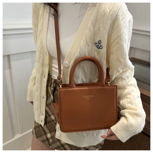 Detail view of brown faux leather crossbody bag with top handle and gold logo lettering