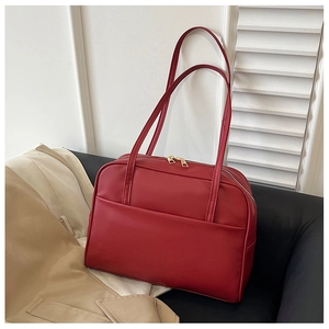 Détail d'un sac bandoulière en cuir rouge foncé avec double fermeture éclair dorée