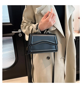 Detailansicht der schwarzen Ledertasche mit Wellennaht und rundem Metallgriff