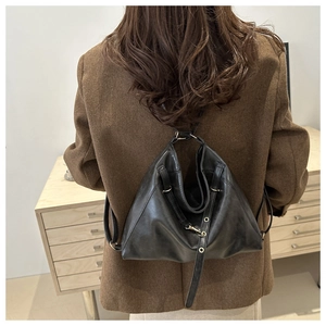 Model wearing soft black leather backpack tote featuring gold ring hardware and pleats
