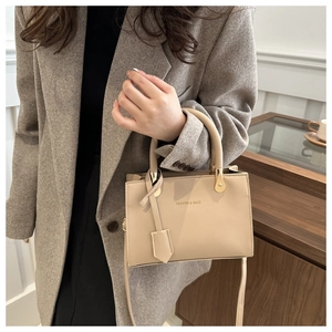 Close-up of beige crossbody bag with gold hardware and FASHION & BAGS gold lettering