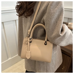Detail of beige faux leather handbag with FASHION & BAGS logo and dual handles