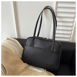 Détail du sac cabas en cuir noir mat minimaliste avec fines bandoulières et poche avant
