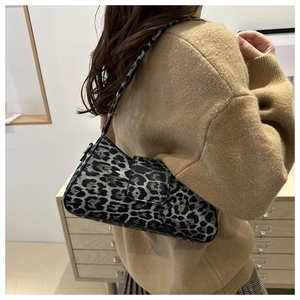 Detailansicht der Schultertasche mit Leopardenmuster an Model mit beigem Strickpullover