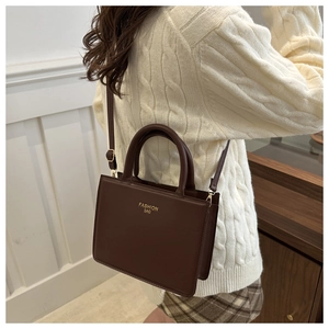 Detailed side view of a dark brown rectangular crossbody bag worn over a beige sweater