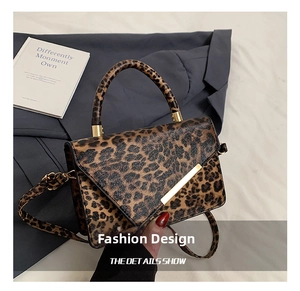 Detail of leopard print crossbody bag with asymmetric flap and gold metal bar accent