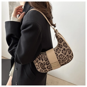 Detailed side view of leopard print crescent bag styled with a professional black suit