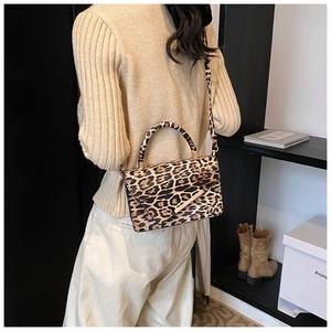 Détail du sac bandoulière léopard avec bordure métallique porté par un mannequin stylé