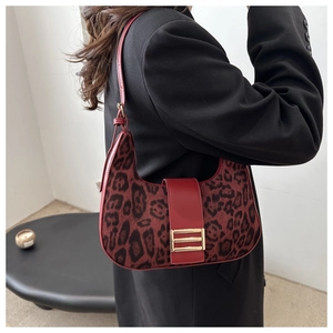 Close-up of red leopard print crescent bag with leather straps and gold buckle details