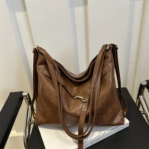 Brown soft leather tote bag with gold hardware and multiple straps on a book