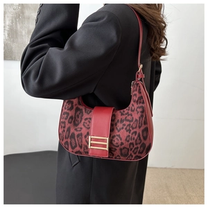 Detail of red leopard print hobo bag with gold metal buckle on black blazer background