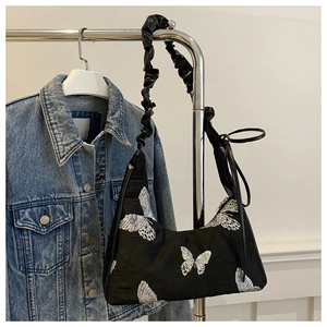 Detail of silver butterfly embroidery on black satin hobo bag with ruched strap