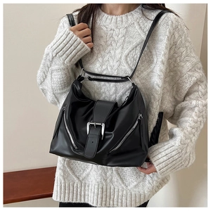 Retro black leather crescent hobo bag with silver buckle and zippers on white sweater