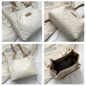 Detail of beige quilted tote bag featuring chain strap and spacious interior compartments